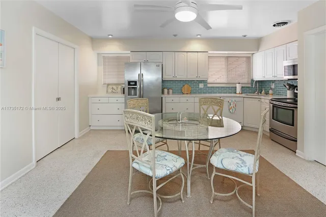 a kitchen with stainless steel appliances a dining table chairs refrigerator and microwave
