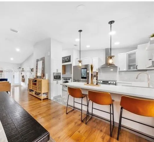 a kitchen with stainless steel appliances kitchen island granite countertop a table chairs sink and cabinets
