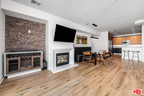 a living room with furniture a fireplace a flat screen tv and kitchen view