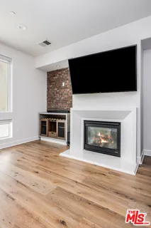 a view of an empty room with wooden floor and a fireplace