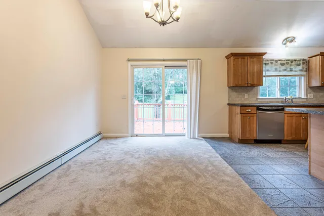 an empty room with kitchen view and a window