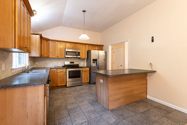 a kitchen with stainless steel appliances granite countertop a sink a stove and a refrigerator