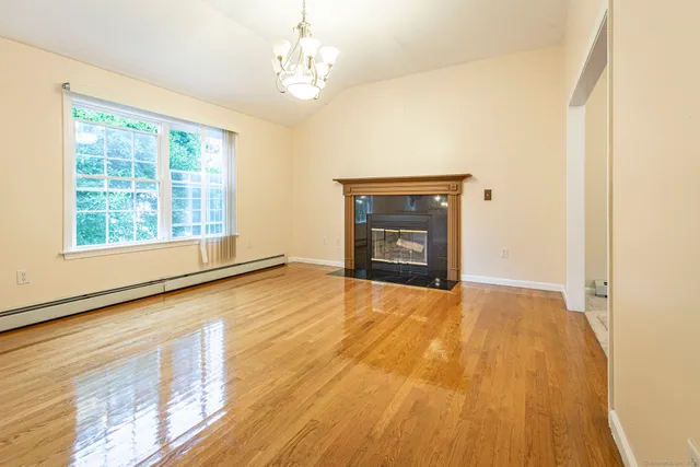 a view of empty room with a fireplace and wooden floor