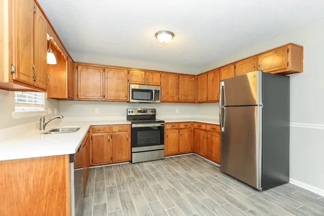 a kitchen with granite countertop wooden floors stainless steel appliances and a sink