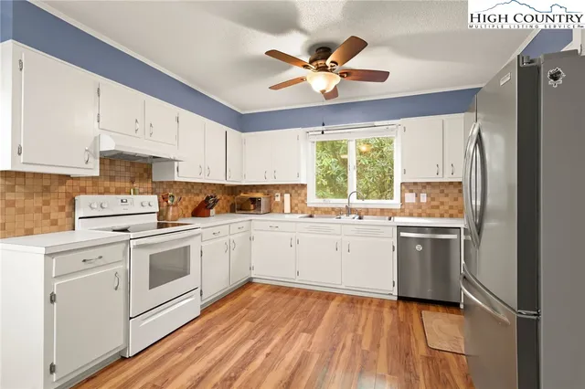 a kitchen with a stove white cabinets and white appliances