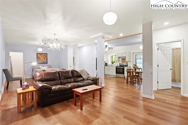 a living room with furniture kitchen view and a chandelier