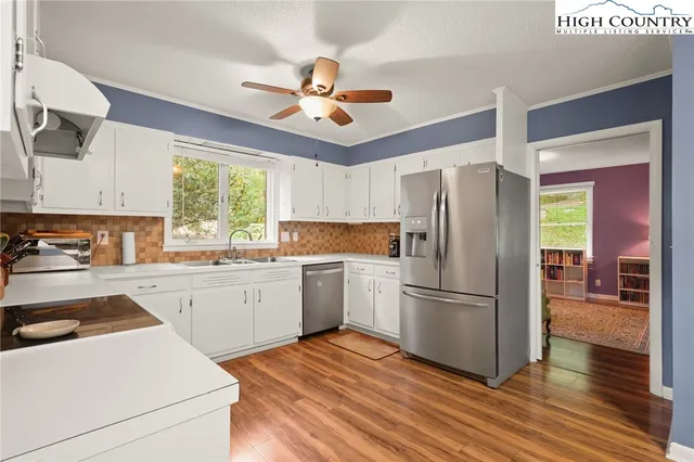 a kitchen with a refrigerator a sink and dishwasher with wooden floor
