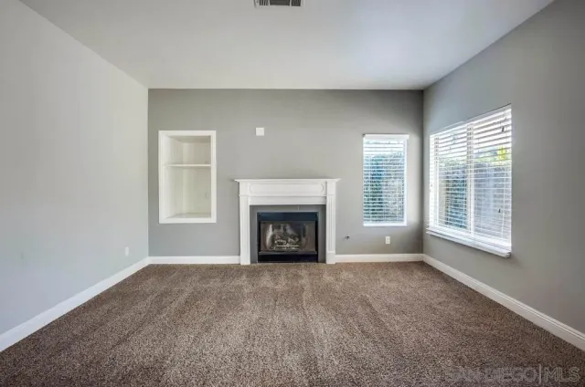 a view of an empty room with a window and fireplace