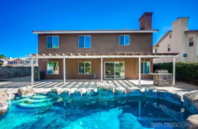 a front view of a house with swimming pool and furniture