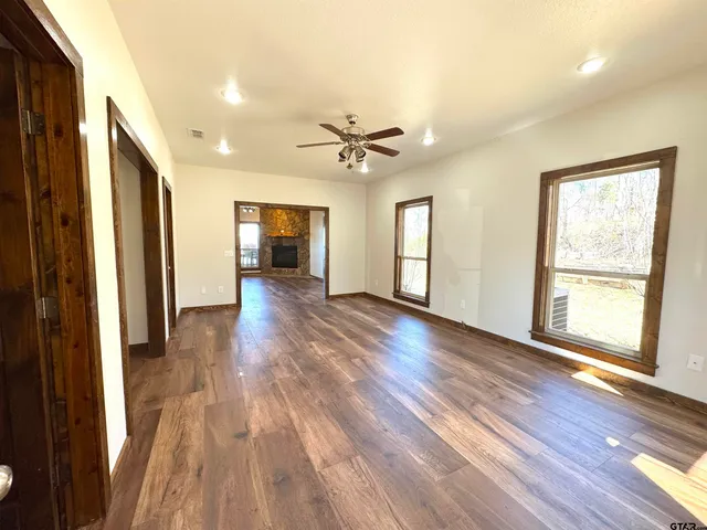 a view of a big room with wooden floor a ceiling fan and windows