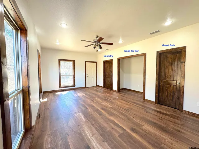 an empty room with wooden floor and a ceiling fan