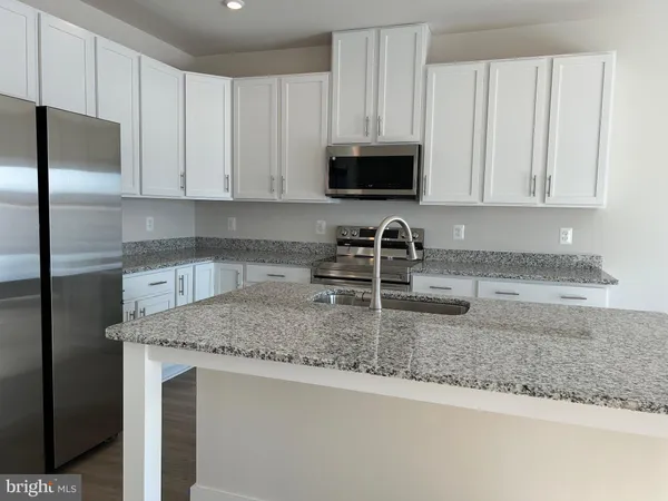 a kitchen with stainless steel appliances granite countertop white cabinets a refrigerator and a sink