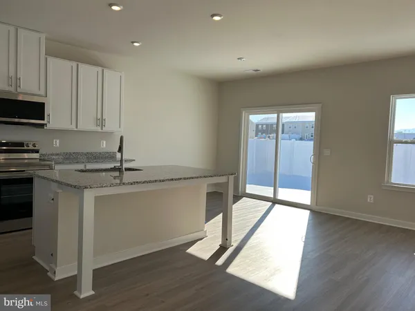 a kitchen with granite countertop a stove a sink and white cabinets with wooden floor