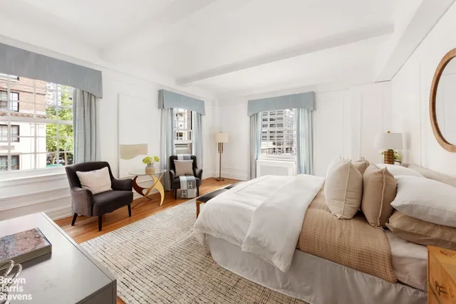 a bedroom with a bed a couch and large windows