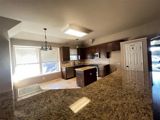 a large kitchen with stainless steel appliances kitchen island granite countertop a refrigerator and a sink