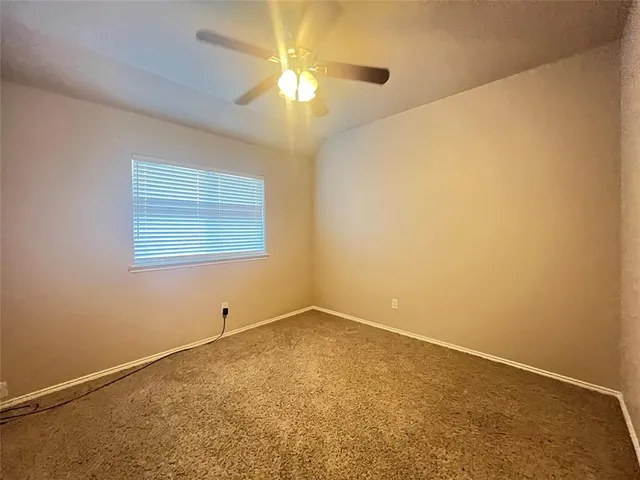 an empty room with a chandelier fan and windows