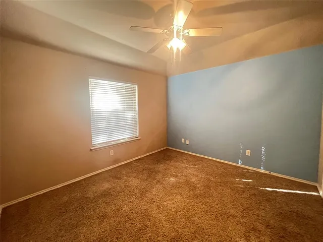 an empty room with a chandelier fan and windows