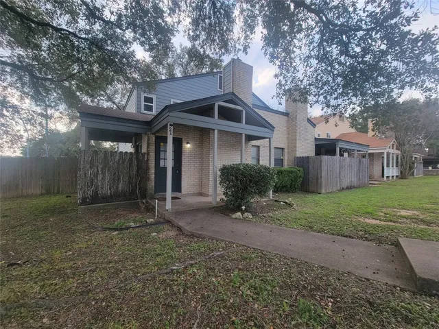 a view of a house with a yard and large tree