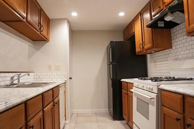 a kitchen with stainless steel appliances granite countertop a sink a stove and a refrigerator