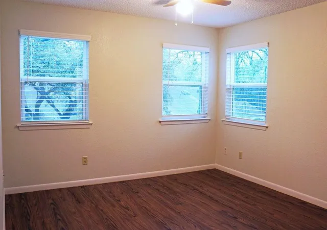 an empty room with wooden floor and windows