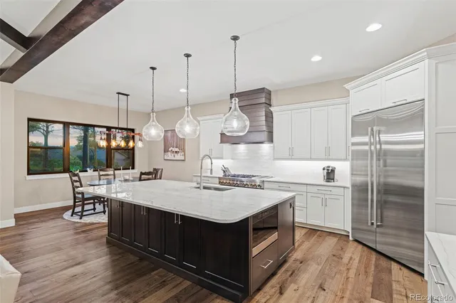 a kitchen with a stove a sink a refrigerator and chairs