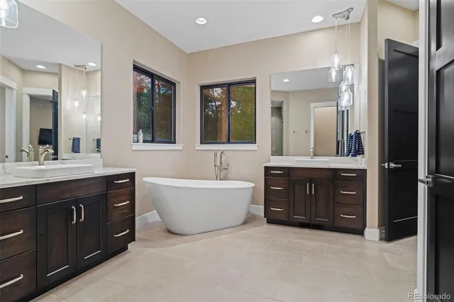 a bathroom with a tub sink double vanity granite and a large mirror