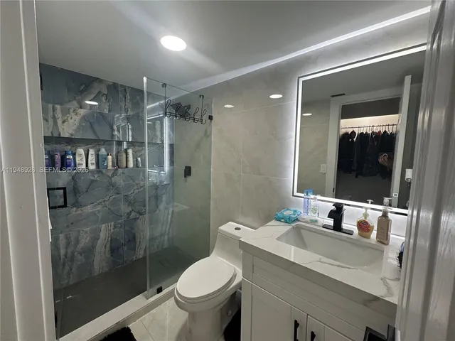 a bathroom with a granite countertop sink toilet and shower