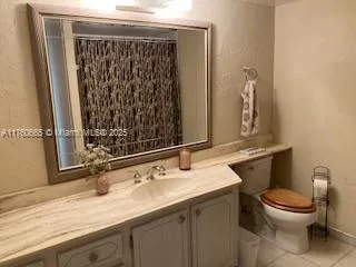 a bathroom with a granite countertop sink a toilet and a mirror