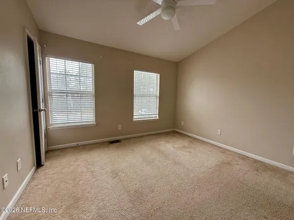an empty room with windows and fan