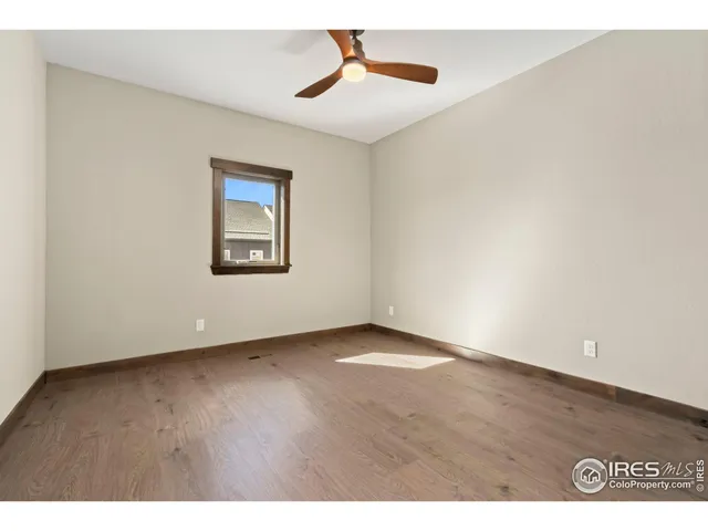 a view of an empty room with chandelier fan and a window