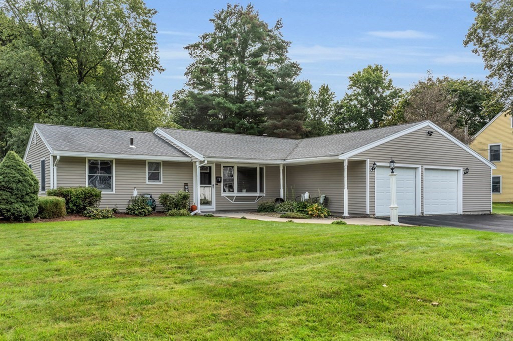 a front view of a house with a garden and trees