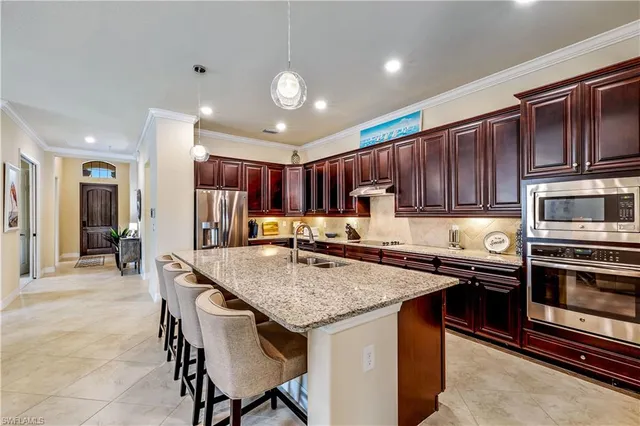 a kitchen with stainless steel appliances granite countertop a table chairs sink refrigerator and cabinets