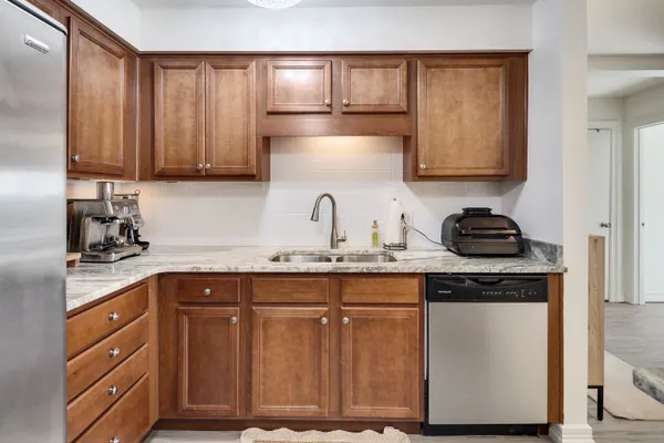 a kitchen with granite countertop a sink cabinets and stainless steel appliances