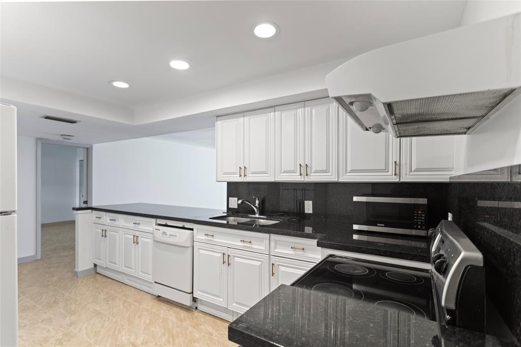 6300 Northwest 2nd Avenue, Unit 405 Boca Raton, FL 33487 - Photo 11 of 37 a kitchen with granite countertop a sink a stove and cabinets