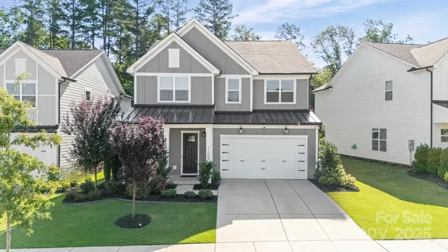a view of a white house with a yard plants and large tree
