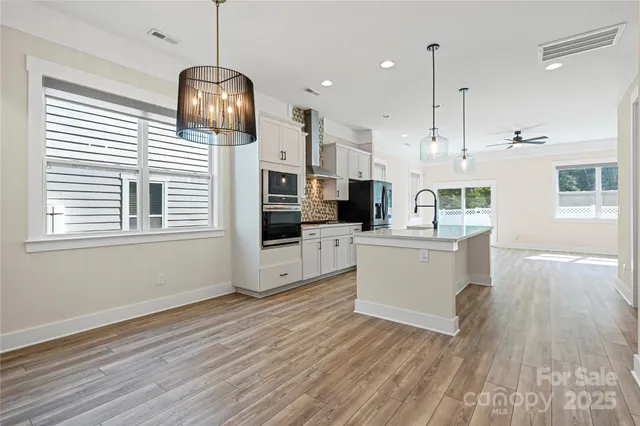 a kitchen with kitchen island stainless steel appliances a stove a sink a center island and wooden floor