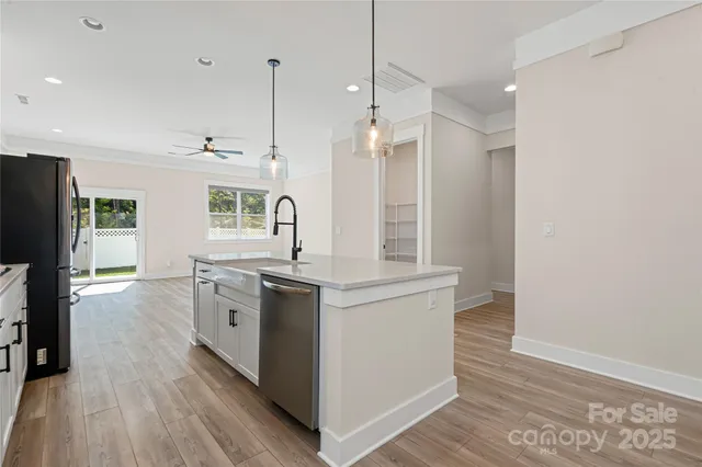 a kitchen with stainless steel appliances granite countertop a sink a stove a refrigerator and white cabinets with wooden floor