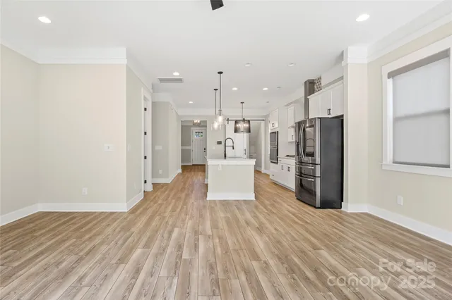 a view of a kitchen with refrigerator and wooden floor