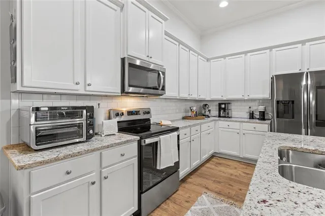 a kitchen with granite countertop white cabinets and stainless steel appliances