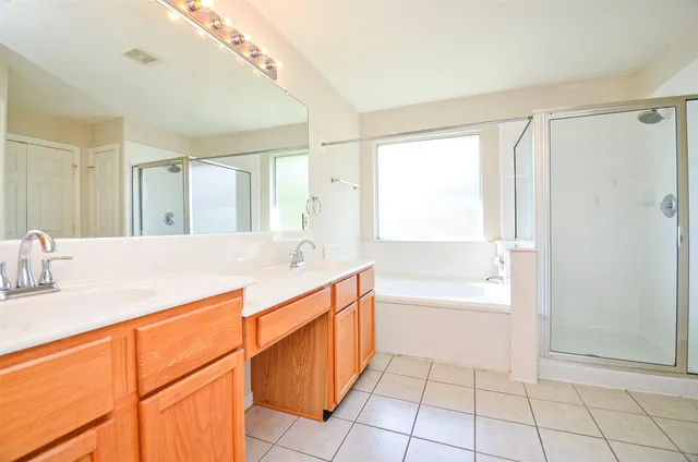 a spacious bathroom with a granite countertop sink a mirror a bathtub and next to a window