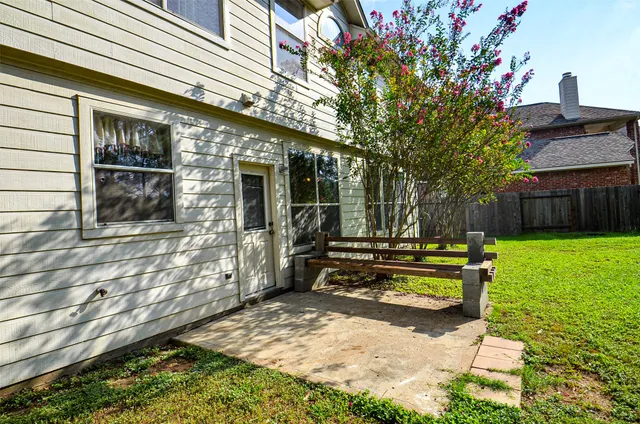 a view of a house with backyard wooden fence and a large tree