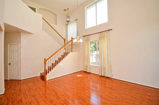 a view of an empty room with wooden floor and fan