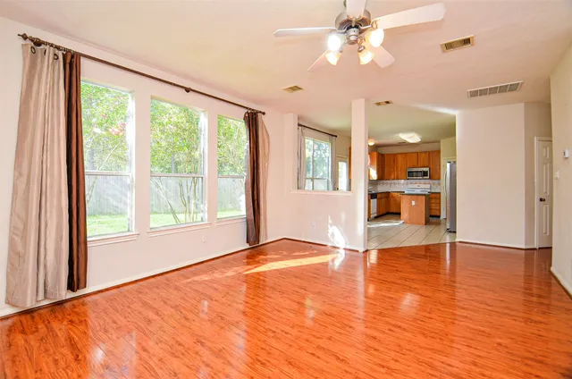 a view of an empty room with window and wooden floor