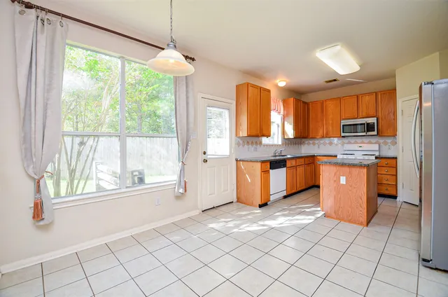 a large kitchen with kitchen island granite countertop a stove a sink dishwasher and a refrigerator