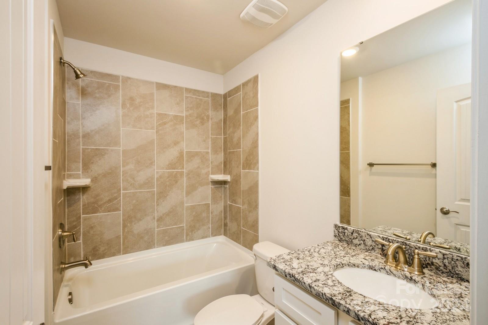 131 Brixham Loop Troutman, NC 28166 - Photo 21 of 26 a bathroom with a granite countertop tub sink toilet and a mirror