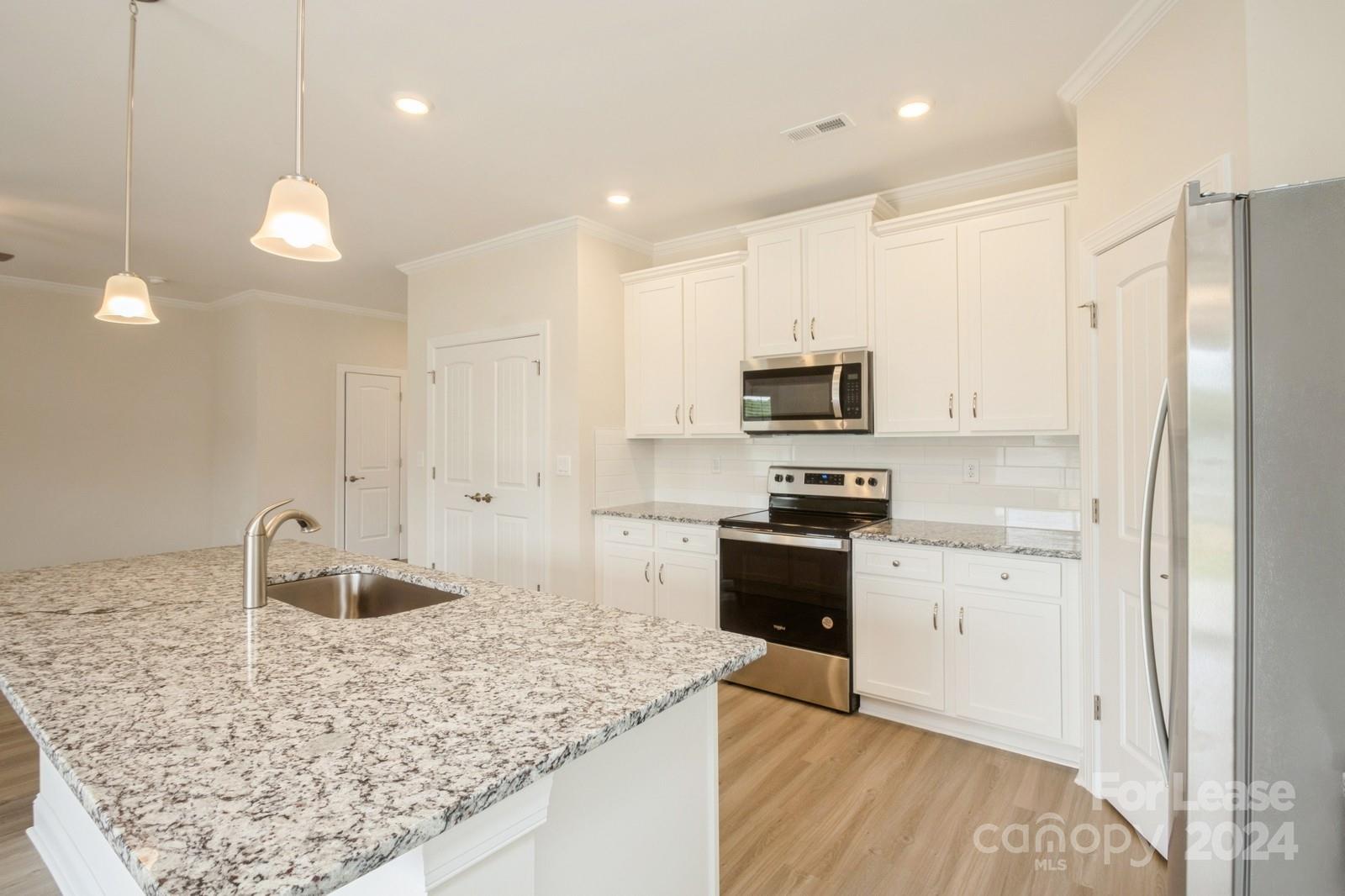 131 Brixham Loop Troutman, NC 28166 - Photo 7 of 26 a kitchen with stainless steel appliances granite countertop a sink stove and refrigerator