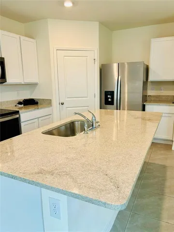 a kitchen with granite countertop a sink a stove and refrigerator