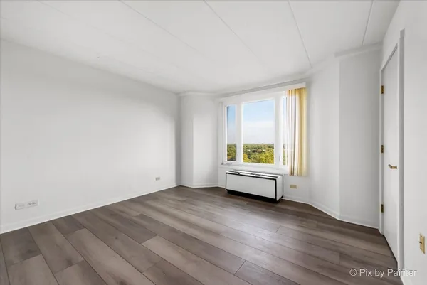 a view of empty room with wooden floor and window