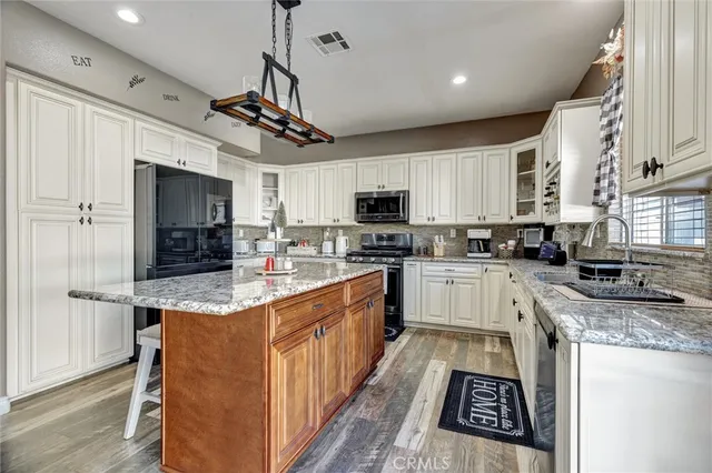 a kitchen with stainless steel appliances granite countertop a refrigerator a stove top oven a sink and dishwasher