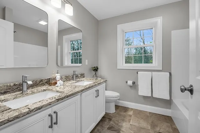 a bathroom with a granite countertop sink toilet and mirror